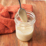 Copycat Texas Roadhouse Honey Mustard in a small mason jar with a spoon in it.