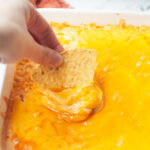 A hand scooping a chip into buffalo turkey dip.