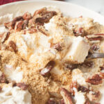 Fall Cheesecake Fruit Salad in a white bowl wiht a spoon scooping it.