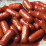 An up close photograph of crockpot little smokies with brown sugar.