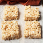 Maple rice krispie treats on a white background with an orange linen behind them.