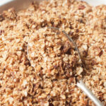A spoon scooping brown sugar granola in a bowl.