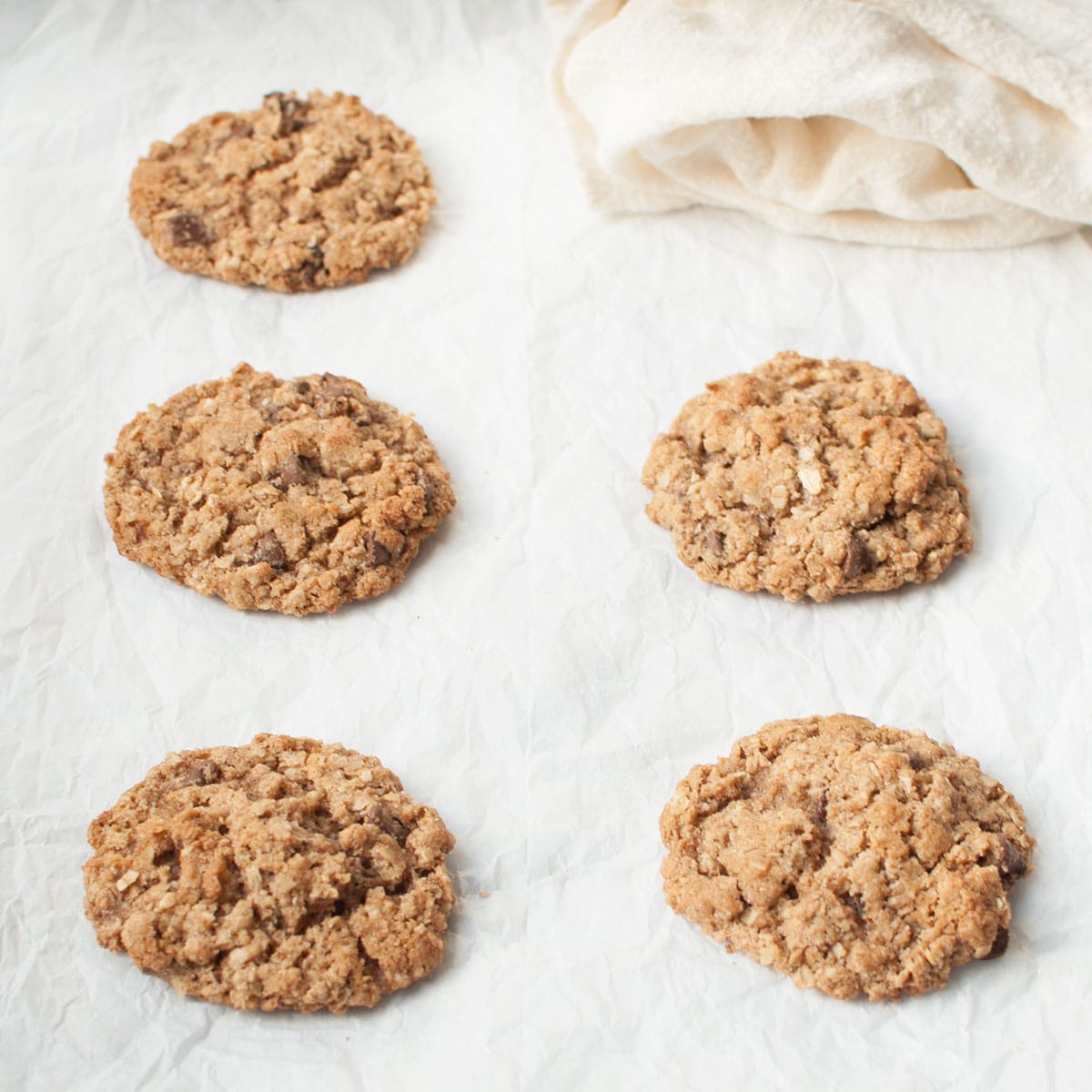 Wheat germ cookies on a white background with a cream linen behind them.