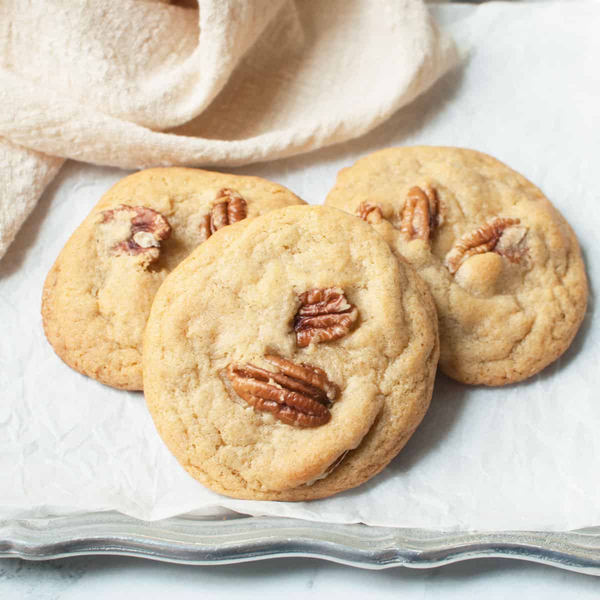Old fashioned pecan cookies on a silver tray with a cream linen.