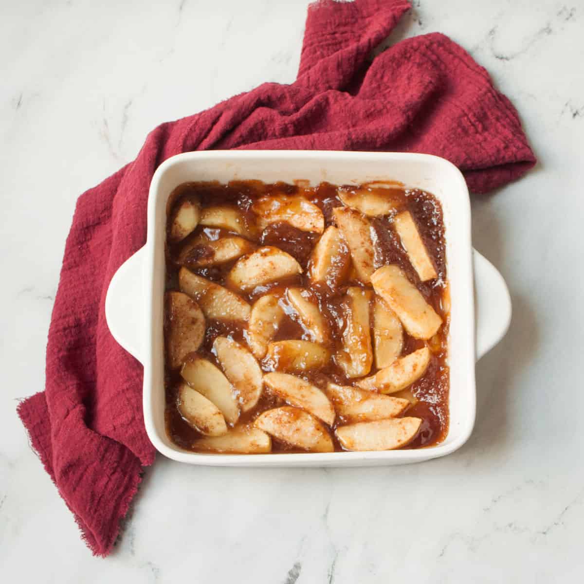 Copycat Boston Market Cinnamon Apples in a white dish with a red linen behind it.