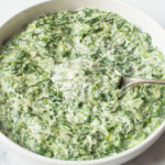Copycat Boston Market Creamed Spinach in a white bowl with a spoon.