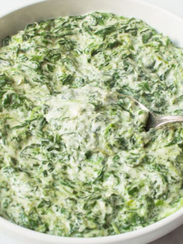 Copycat Boston Market Creamed Spinach in a white bowl with a spoon.