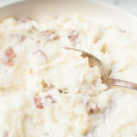 A spoon scooping Copycat Cheesecake Factory Mashed Potatoes.