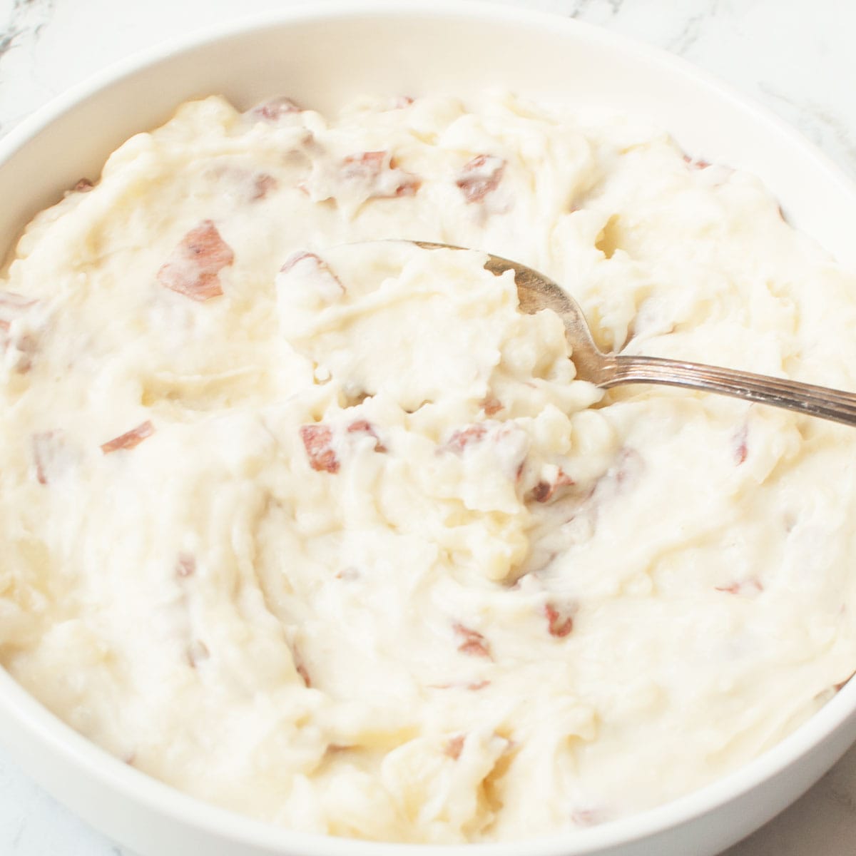 A spoon scooping Copycat Cheesecake Factory Mashed Potatoes.