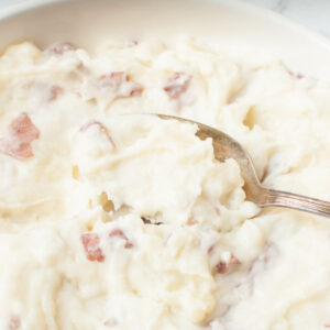 A spoon scooping Copycat Cheesecake Factory Mashed Potatoes.