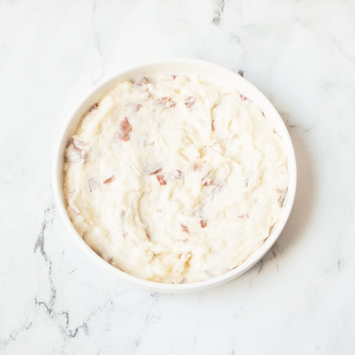 Copycat Cheesecake Factory Mashed Potatoes in a white bowl on a marble background.