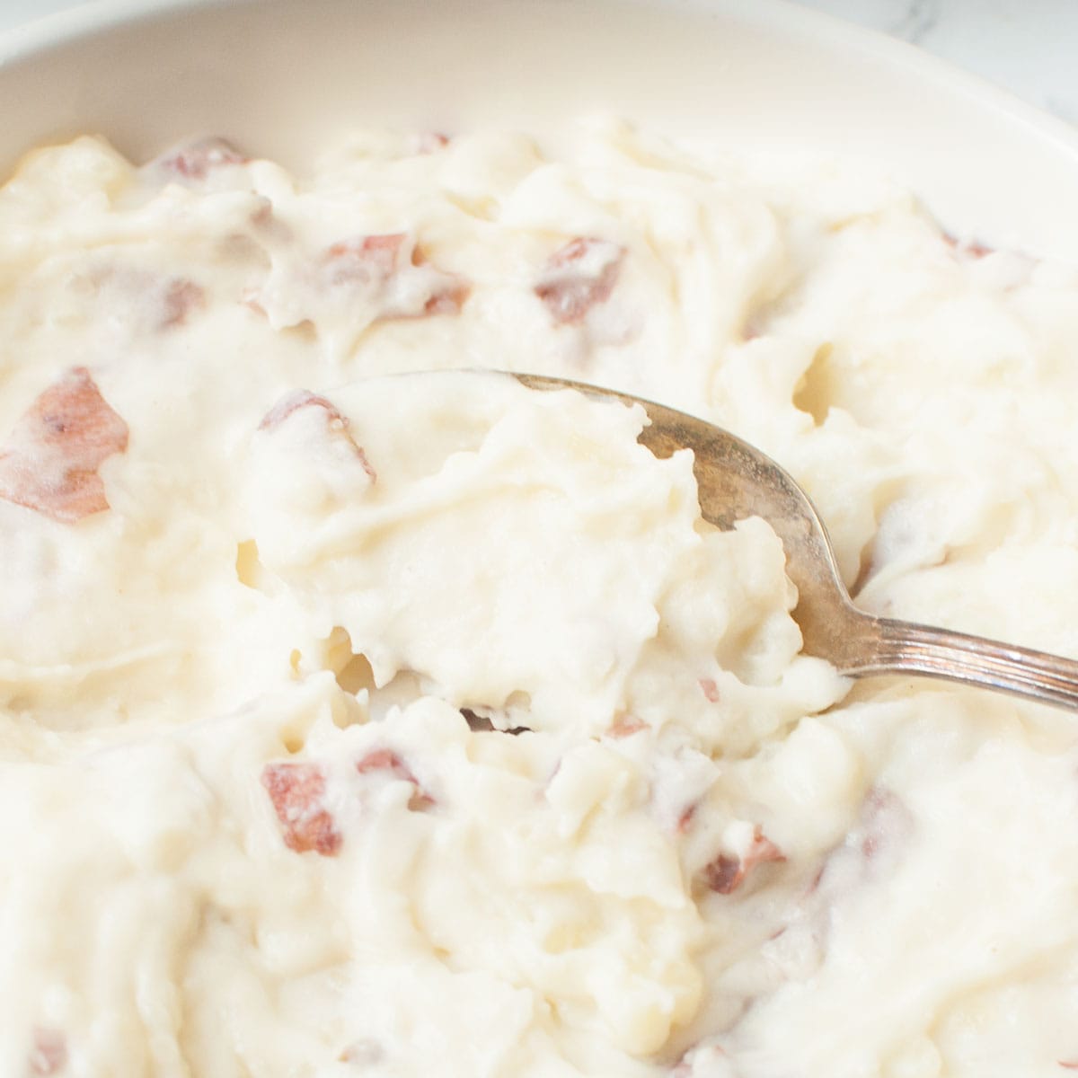 A spoon scooping Copycat Cheesecake Factory Mashed Potatoes.