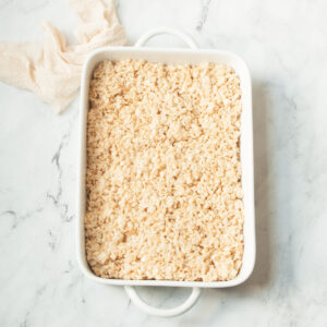 Rice Krispie treats in a 9-13 inch on a marble background with a cream linen.