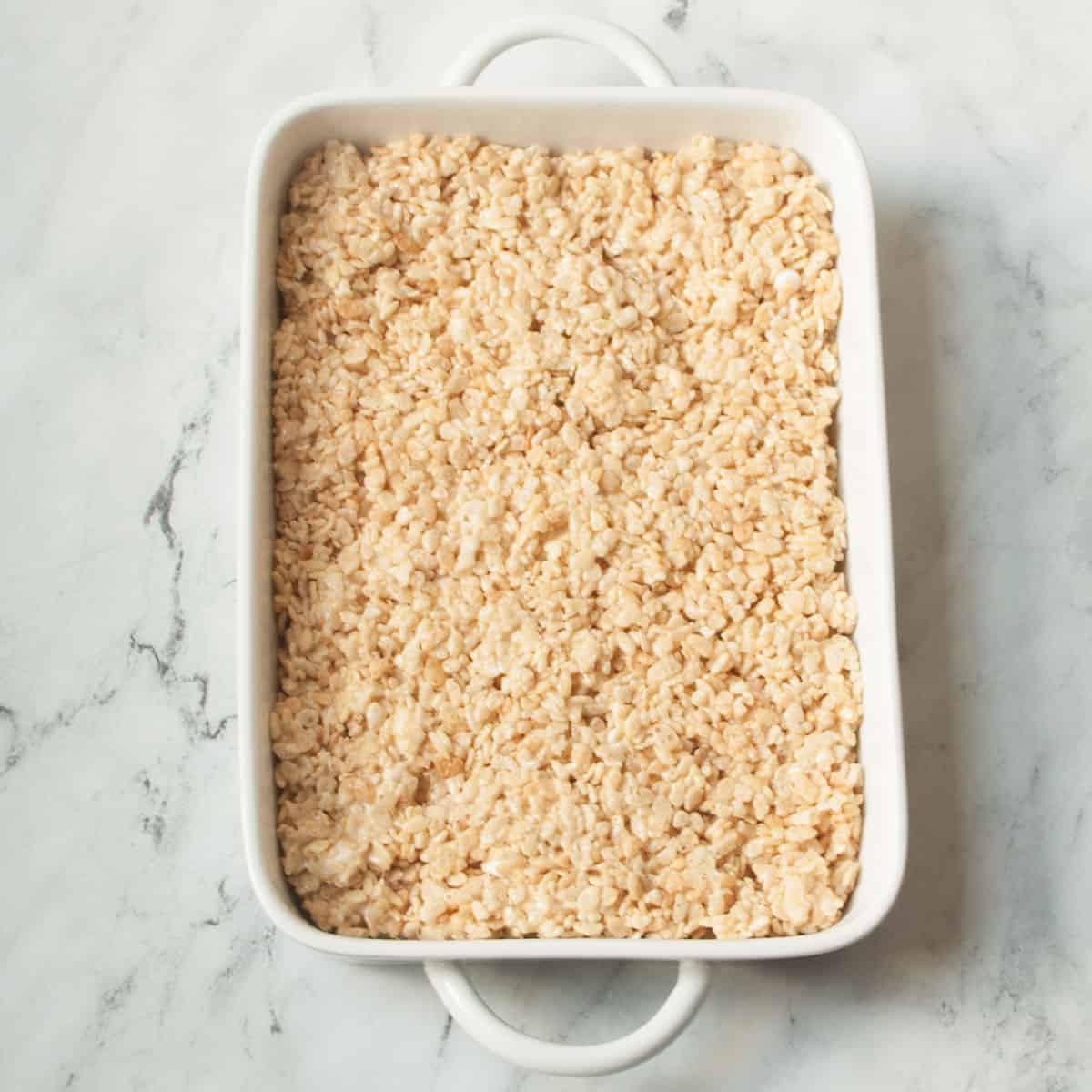Rice Krispie treats in a 9-13 inch on a marble background.