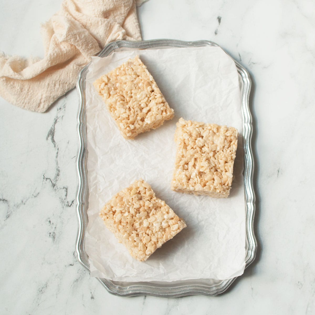 Rice Krispie treat squares on a tray on a marble background.