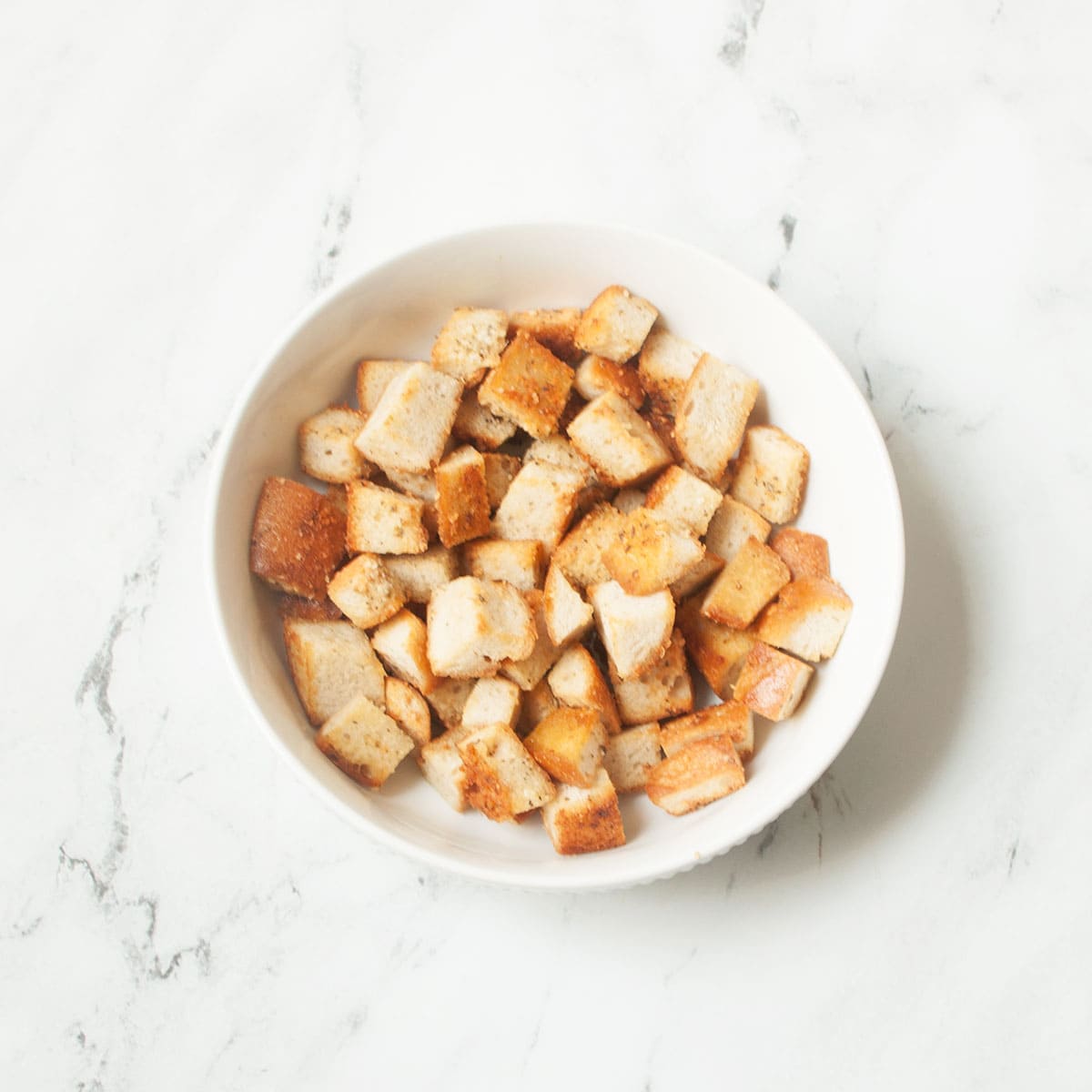Copycat Texas Roadhouse croutons in a white bowl on a marble background.
