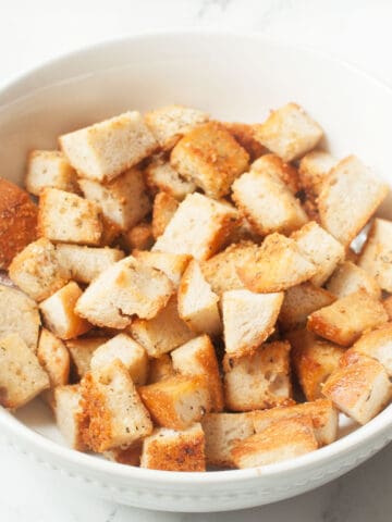 Copycat Texas Roadhouse croutons in a white bowl on a marble background.