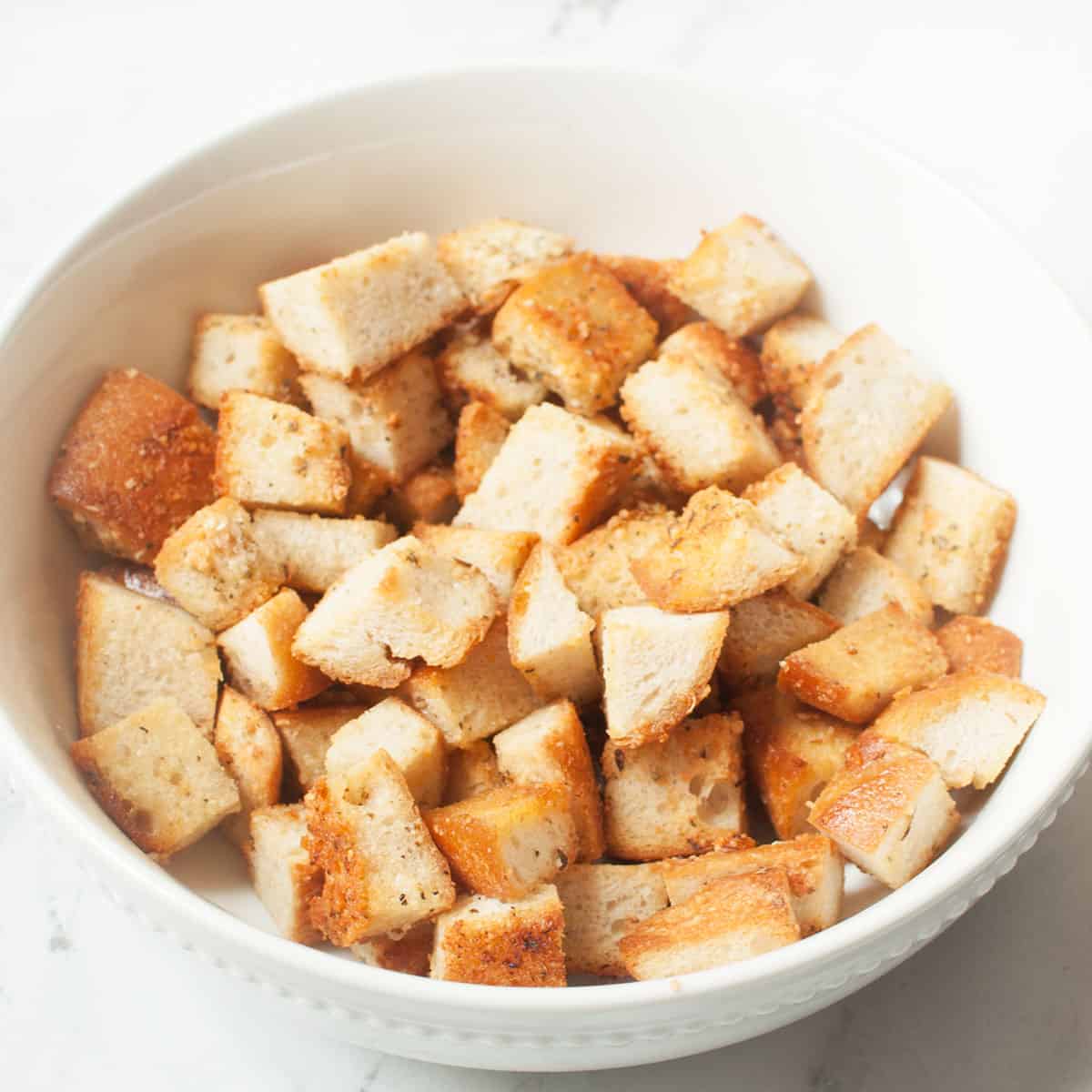 Copycat Texas Roadhouse croutons in a white bowl on a marble background.