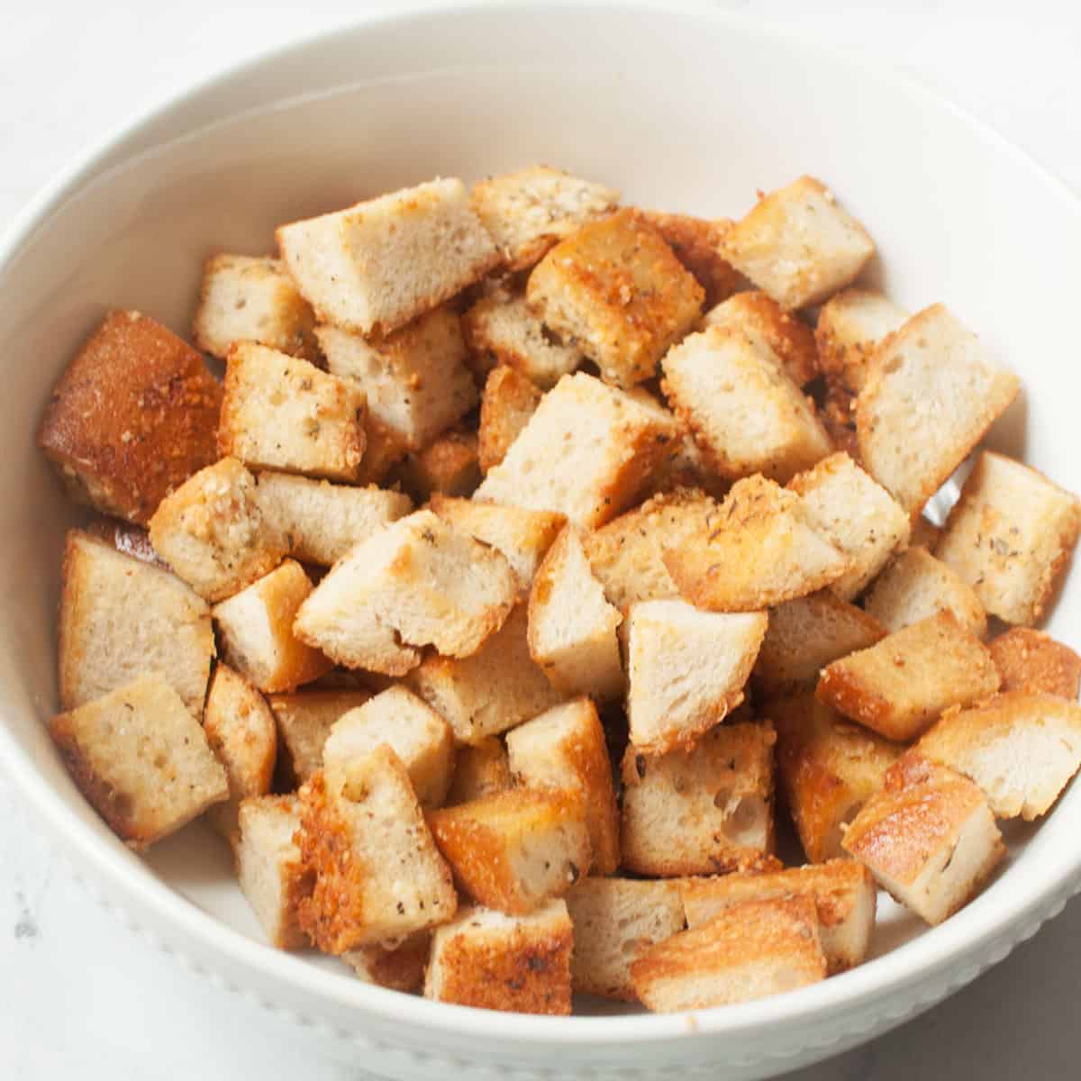 Copycat Texas Roadhouse croutons in a white bowl on a marble background.