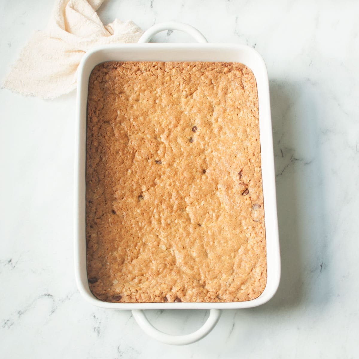 Oatmeal blondies in a white dish on a marble background.